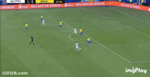 A Soccer Player Is Kneeling On The Field While Another Player Kicks The Ball . GIF