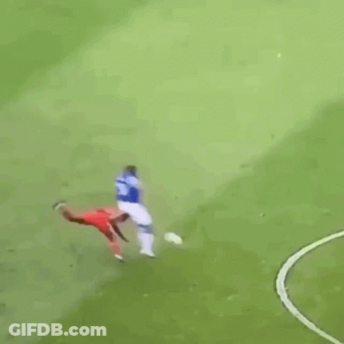 A Soccer Player Is Kneeling On The Field While Another Player Stands Behind Him . GIF