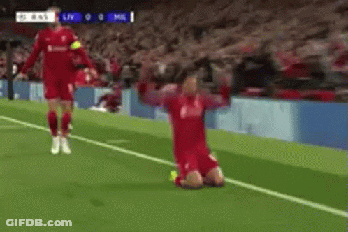 A Soccer Player Is Kneeling On The Field With His Arms Outstretched While Another Player Runs Towards Him . GIF