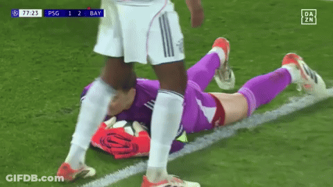 A Soccer Player Is Laying On The Field While Another Player Kicks Him . GIF