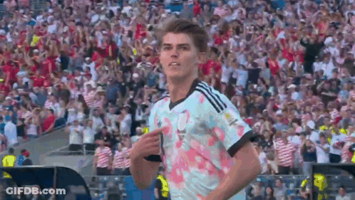 A Soccer Player Is Pointing At The Crowd While Wearing A Jersey With Flowers On It GIF