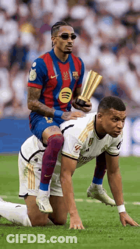 A Soccer Player Is Riding On The Back Of Another Soccer Player On A Field . GIF