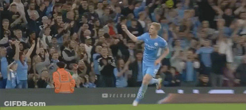 A Soccer Player Is Running In Front Of A Crowd On A Field . GIF