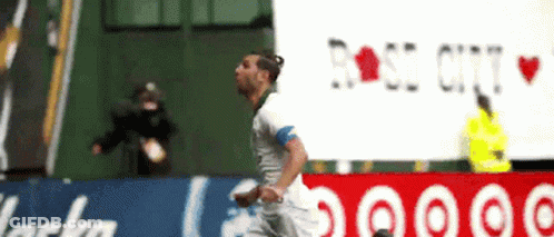 A Soccer Player Is Running In Front Of A Rose City Sign GIF