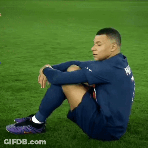 A Soccer Player Is Sitting On The Grass Wearing Purple Nike Shoes GIF