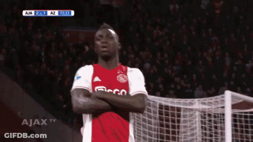 A Soccer Player Is Standing In Front Of A Goal With His Arms Crossed In Front Of A Ajax Tv Screen GIF