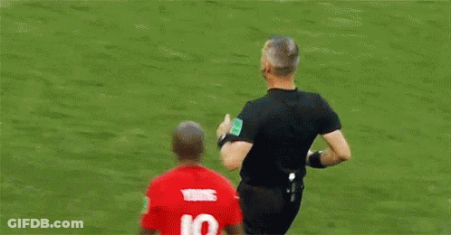 A Soccer Player Is Talking To A Referee On A Field . GIF