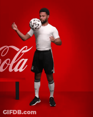 A Soccer Player Kicks A Soccer Ball In Front Of A Coca Cola Sign GIF