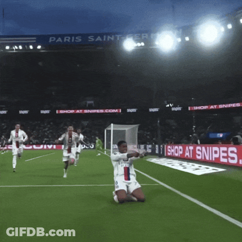 A Soccer Player Kneeling On The Field In Front Of A Paris Saint Germain Sign GIF