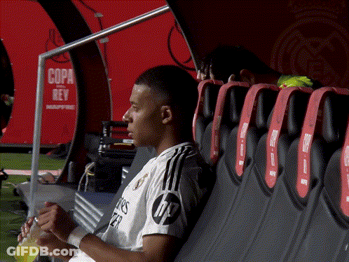 A Soccer Player Sits In A Dugout With A Sign That Says Copa Rey In The Background GIF