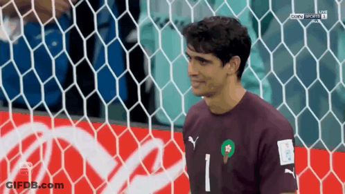 A Soccer Player Stands In Front Of A Coca Cola Advertisement GIF
