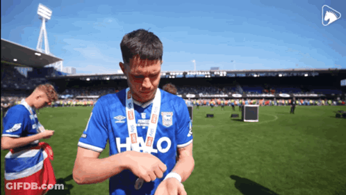 A Soccer Player Wearing A Blue Halo Shirt Looks At His Watch GIF