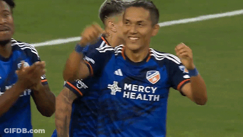 A Soccer Player Wearing A Blue Mercy Health Jersey Is Being Hugged By Another Player . GIF