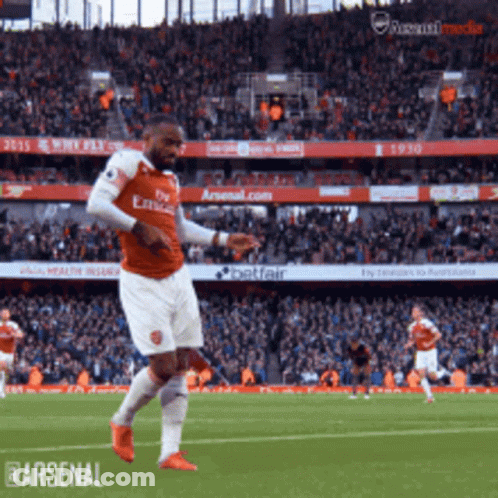 A Soccer Player Wearing A Fly Emirates Jersey Is Kicking A Ball GIF