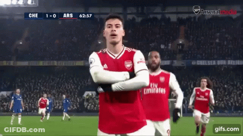 A Soccer Player Wearing A Fly Emirates Jersey Stands On The Field With His Arms Crossed GIF