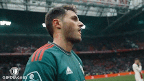 A Soccer Player Wearing A Green Adidas Jersey Is Standing On The Field . GIF