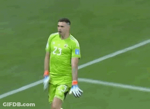 A Soccer Player Wearing A Green Jersey And Gloves Is Standing On A Field . GIF