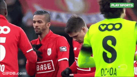 A Soccer Player Wearing A Green Jersey With The Letter S On It Is Talking To Another Player . GIF