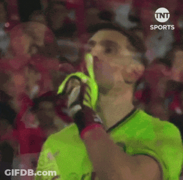 A Soccer Player Wearing A Green Shirt And Yellow Gloves Is Blowing A Kiss GIF