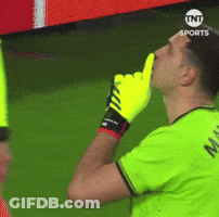 A Soccer Player Wearing A Green Shirt And Yellow Gloves Is Blowing A Whistle GIF