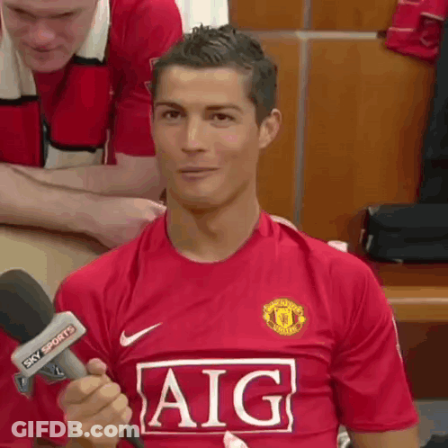 A Soccer Player Wearing A Red Aig Jersey Is Holding A Microphone . GIF