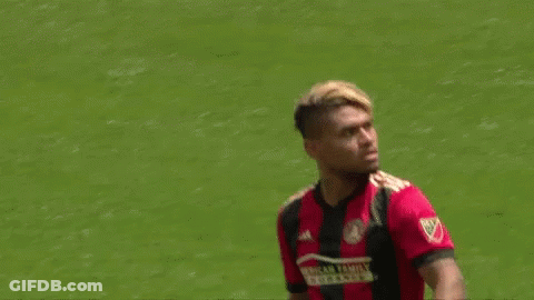 A Soccer Player Wearing A Red And Black Jersey Is Standing On The Field . GIF