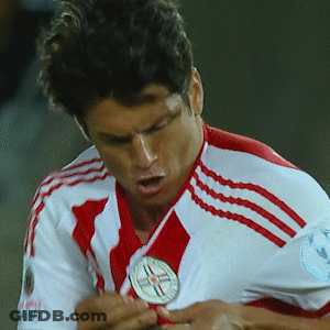 A Soccer Player Wearing A Red And White Jersey Is Holding A Medal GIF