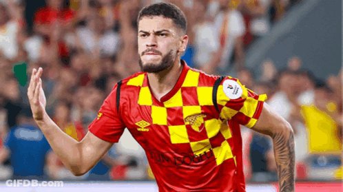 A Soccer Player Wearing A Red And Yellow Checkered Jersey With Umbro Written On It GIF