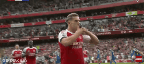A Soccer Player Wearing A Red Emirates Fly Better Jersey Is Standing On The Field . GIF