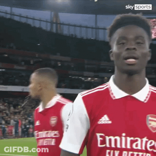 A Soccer Player Wearing A Red Emirates Jersey Stands On The Field GIF