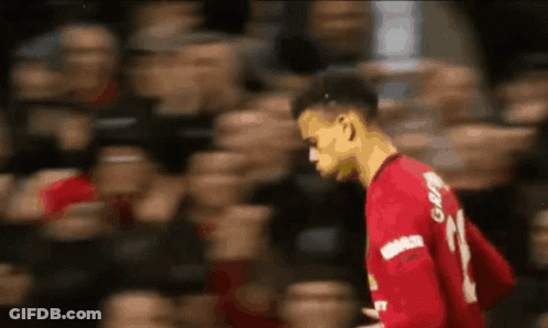 A Soccer Player Wearing A Red Jersey With The Number 21 On It Is Walking In Front Of A Crowd . GIF