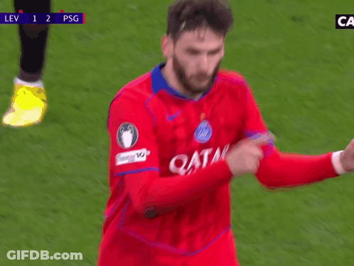 A Soccer Player Wearing A Red Qatar Jersey Is Pointing At Something GIF