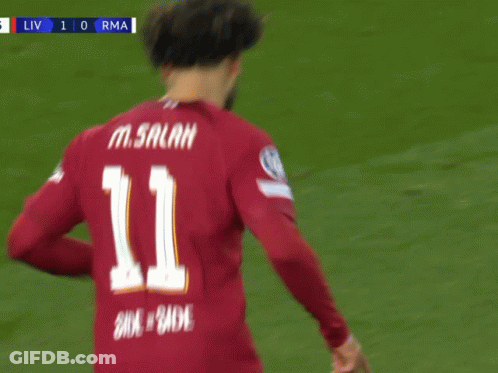 A Soccer Player Wearing A Red Shirt That Says Standard Chartered Is Pointing Up GIF