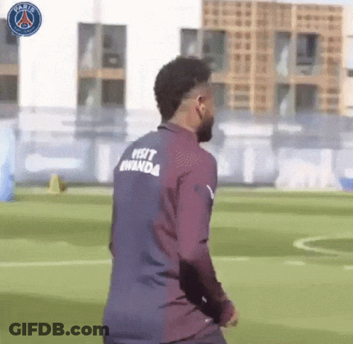 A Soccer Player Wearing A Shirt That Says Visit Rwanda On The Back Is Walking On A Field . GIF