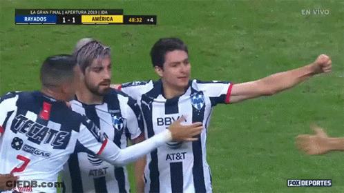 A Soccer Player Wearing A Tecate Jersey Is Hugging Another Player On The Field GIF