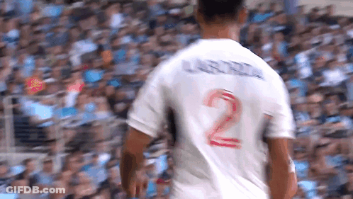 A Soccer Player Wearing A White Jersey With The Number 2 On The Back Is Walking In Front Of A Crowd . GIF