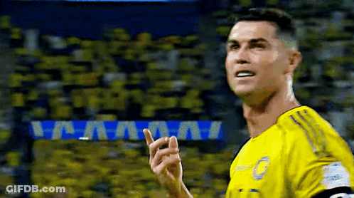 A Soccer Player Wearing A Yellow Jersey Is Pointing Up At The Crowd . GIF