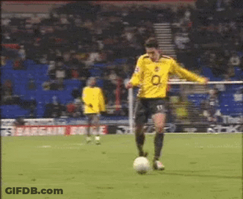 A Soccer Player Wearing A Yellow Jersey With The Number 13 On It Is Kicking A Soccer Ball GIF