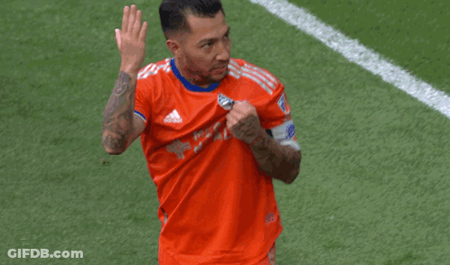A Soccer Player Wearing An Orange Adidas Shirt Is Waving GIF