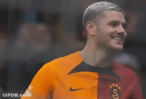 A Soccer Player Wearing An Orange And Red Jersey Is Smiling And Looking To The Side . GIF