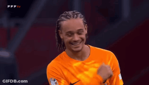 A Soccer Player Wearing An Orange Nike Jersey Is Smiling And Laughing GIF