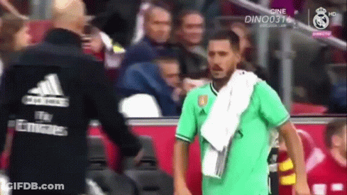 A Soccer Player With A Towel Around His Neck Is Talking To Another Man GIF