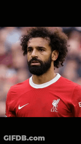 A Soccer Player With Curly Hair And A Beard Is Wearing A Red Shirt . GIF