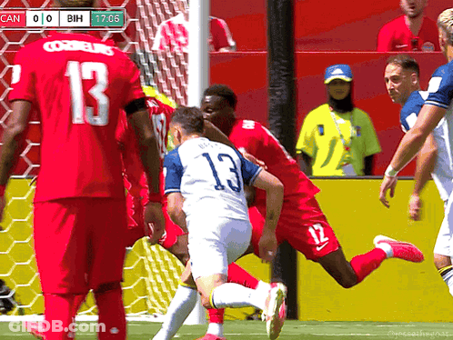 A Soccer Player With The Number 13 On His Jersey Is Being Tackled By Another Player GIF