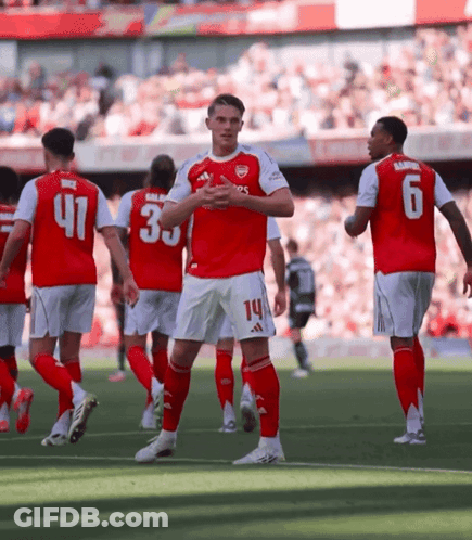 A Soccer Player With The Number 14 On His Shorts Stands On The Field With Other Players GIF
