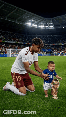 A Soccer Player With The Number 19 On His Jersey Is Kneeling Down With A Baby GIF