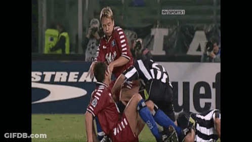 A Soccer Player With The Number 23 On His Back Is Being Tackled By Another Player GIF