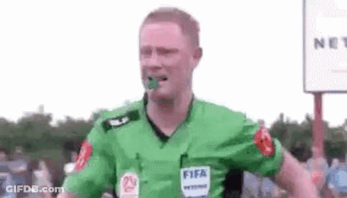 A Soccer Referee Is Wearing A Green Shirt With A Fifa Logo On It And Has A Green Object In His Mouth . GIF