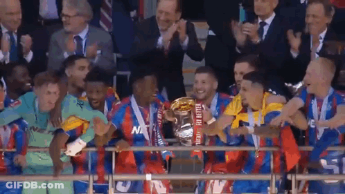 A Soccer Team Is Holding A Trophy In Front Of A Crowd Of People . GIF
