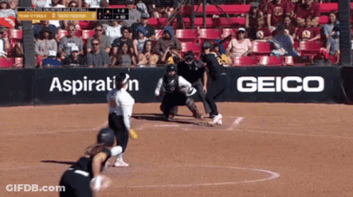 A Softball Game Is Being Played In Front Of A Geico Sign GIF